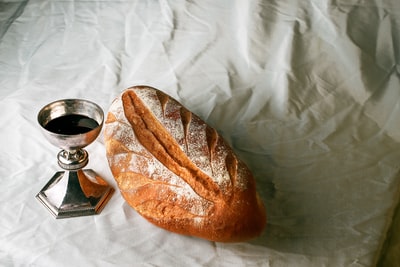 透明玻璃杯旁的白色织物面包